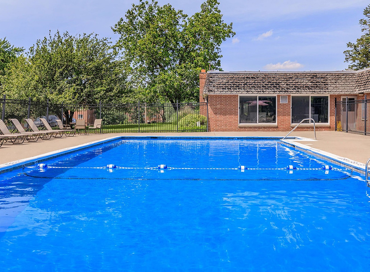 Inviting outdoor pool with sun loungers and lush greenery, offering a perfect relaxation spot.