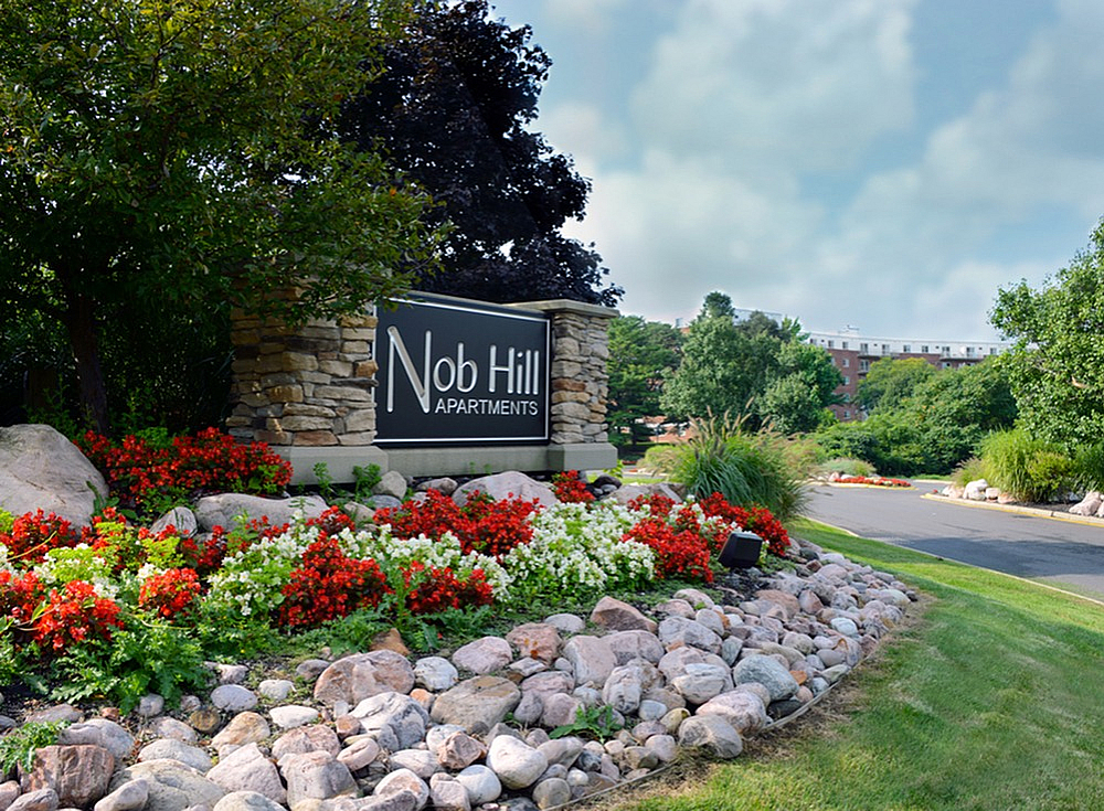 Inviting entrance to Nob Hill Apartments, featuring lush landscaping with vibrant flowers and well-maintained greenery.