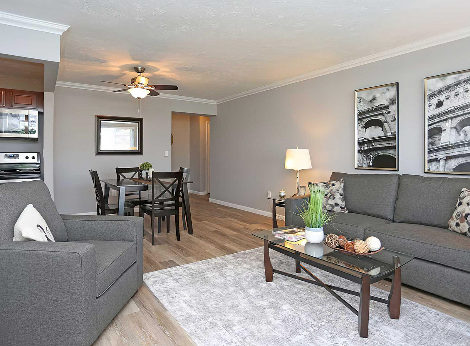 Chic living room with modern decor, featuring a cozy gray sofa, elegant coffee table, and stylish dining area under a ceiling fan.