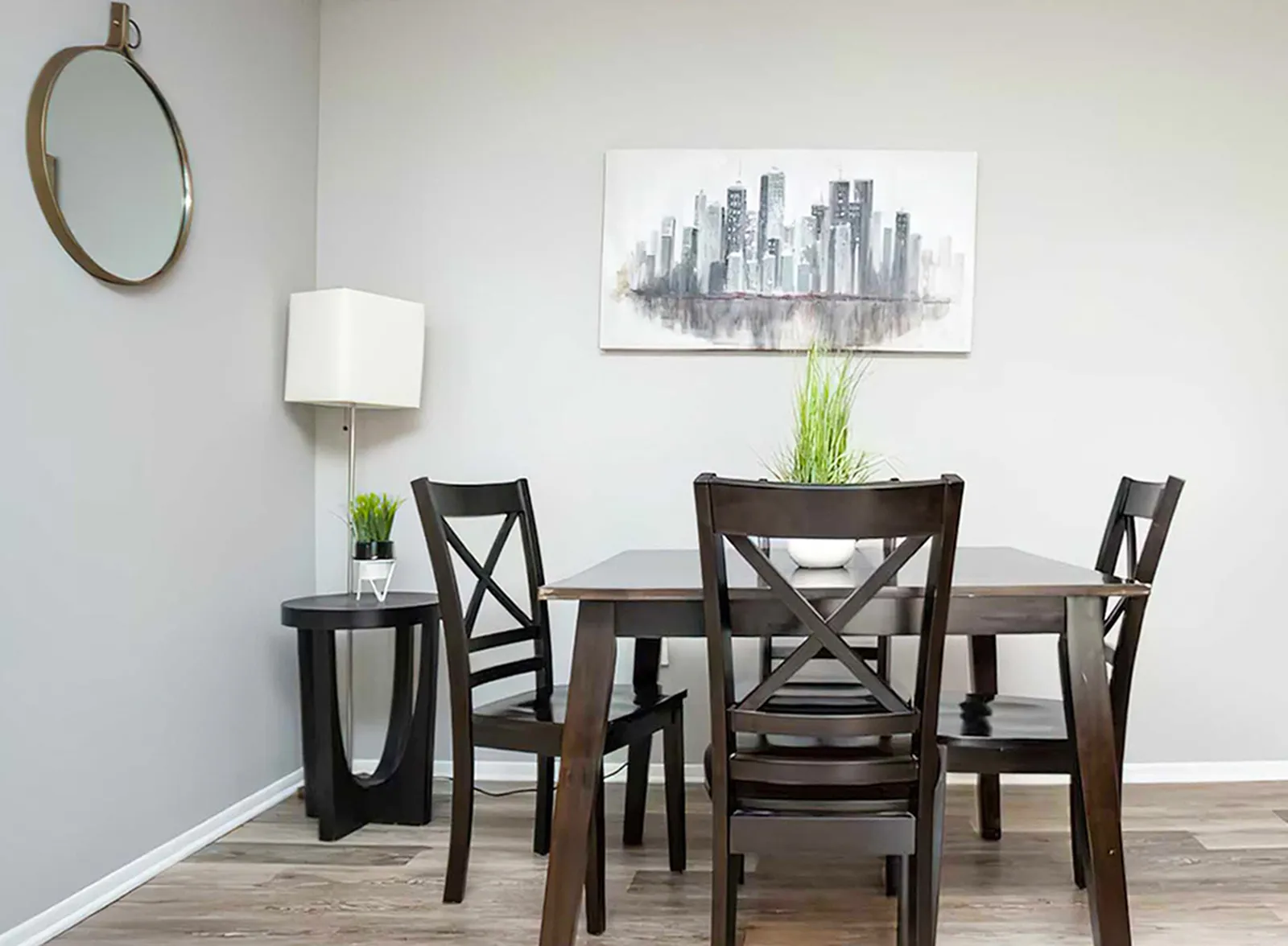 Bright and modern dining room featuring sleek dark wood furniture, a contemporary cityscape painting, and elegant decor accents.