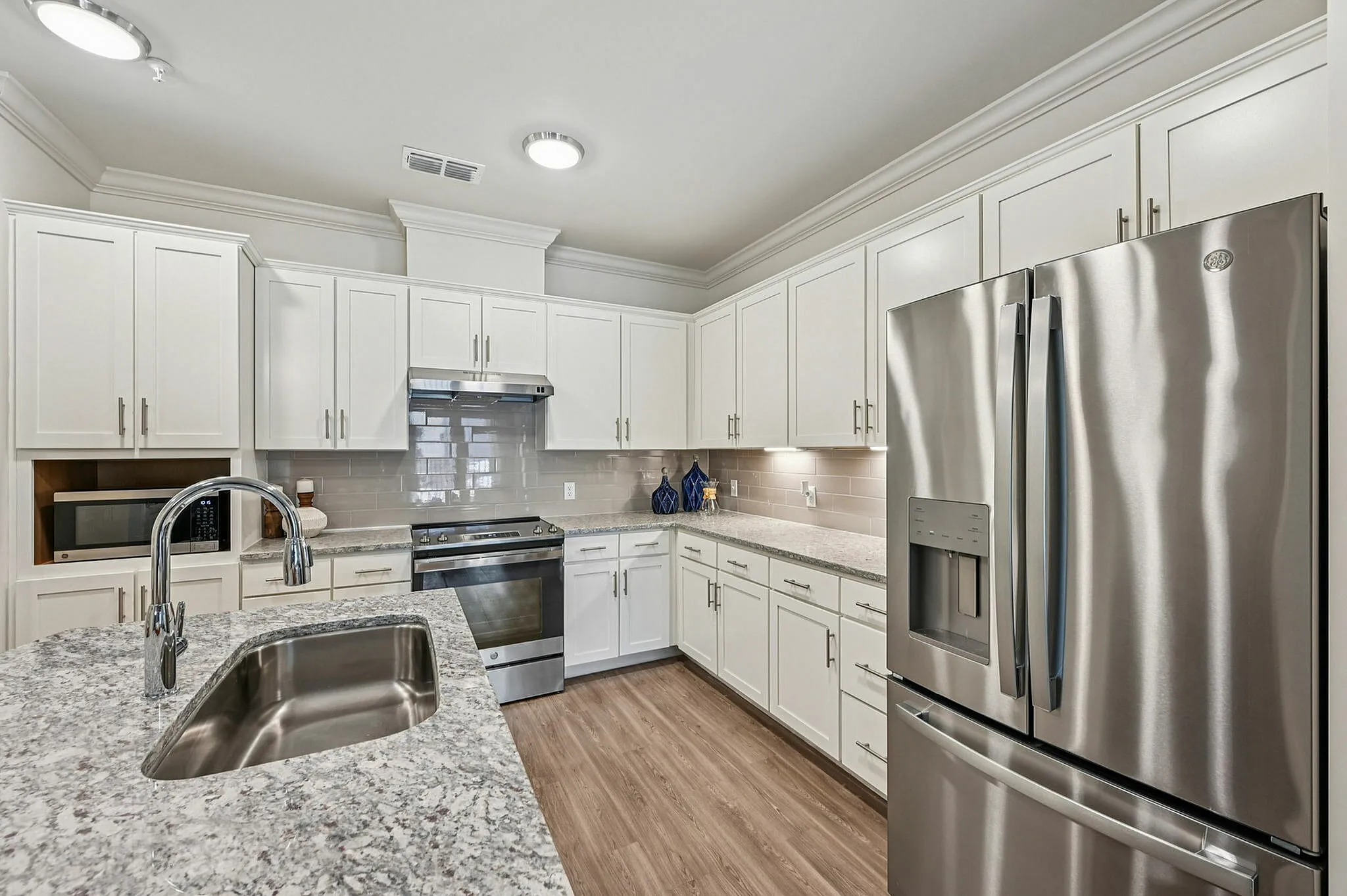 Elegant modern kitchen with stainless steel appliances, sleek granite countertops, and white cabinetry, ideal for culinary enthusiasts.