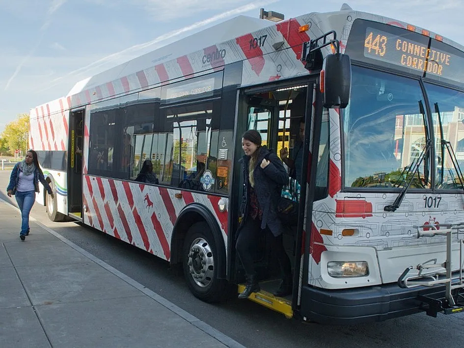 Vibrant city bus with modern design as passengers disembark at a sunny urban stop.