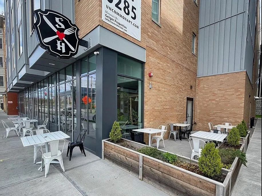 Modern commercial building with outdoor seating area and decorative planters, showcasing a stylish urban design.
