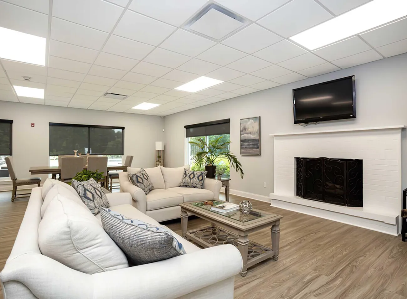 Inviting open-concept living space with elegant sofas, contemporary decor, large windows, and a cozy fireplace.