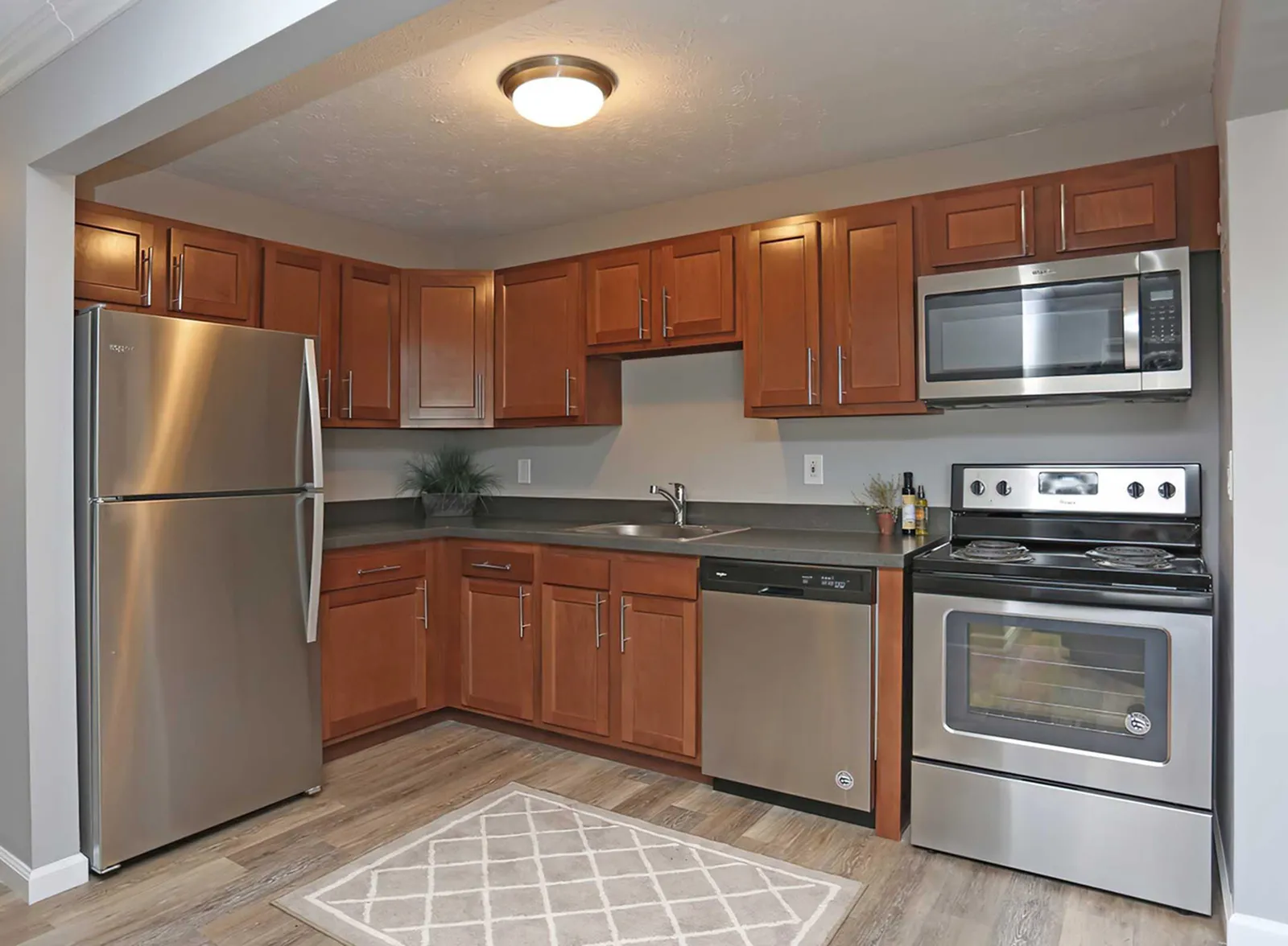 Modern kitchen with stainless steel appliances, sleek gray countertops, and rich wooden cabinetry creating an inviting cooking space.