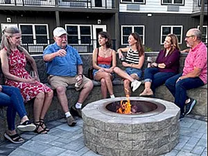 Vibrant community gathering around a cozy fire pit at a modern apartment complex with stylish balconies.