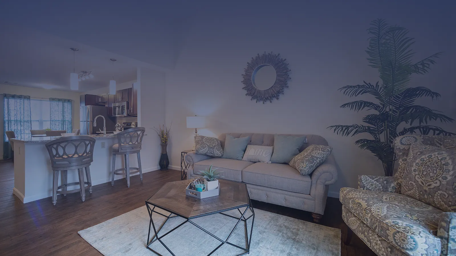 Inviting living room with elegant furniture, stylish rug, and a modern open-plan kitchen with sleek design and bar stools.