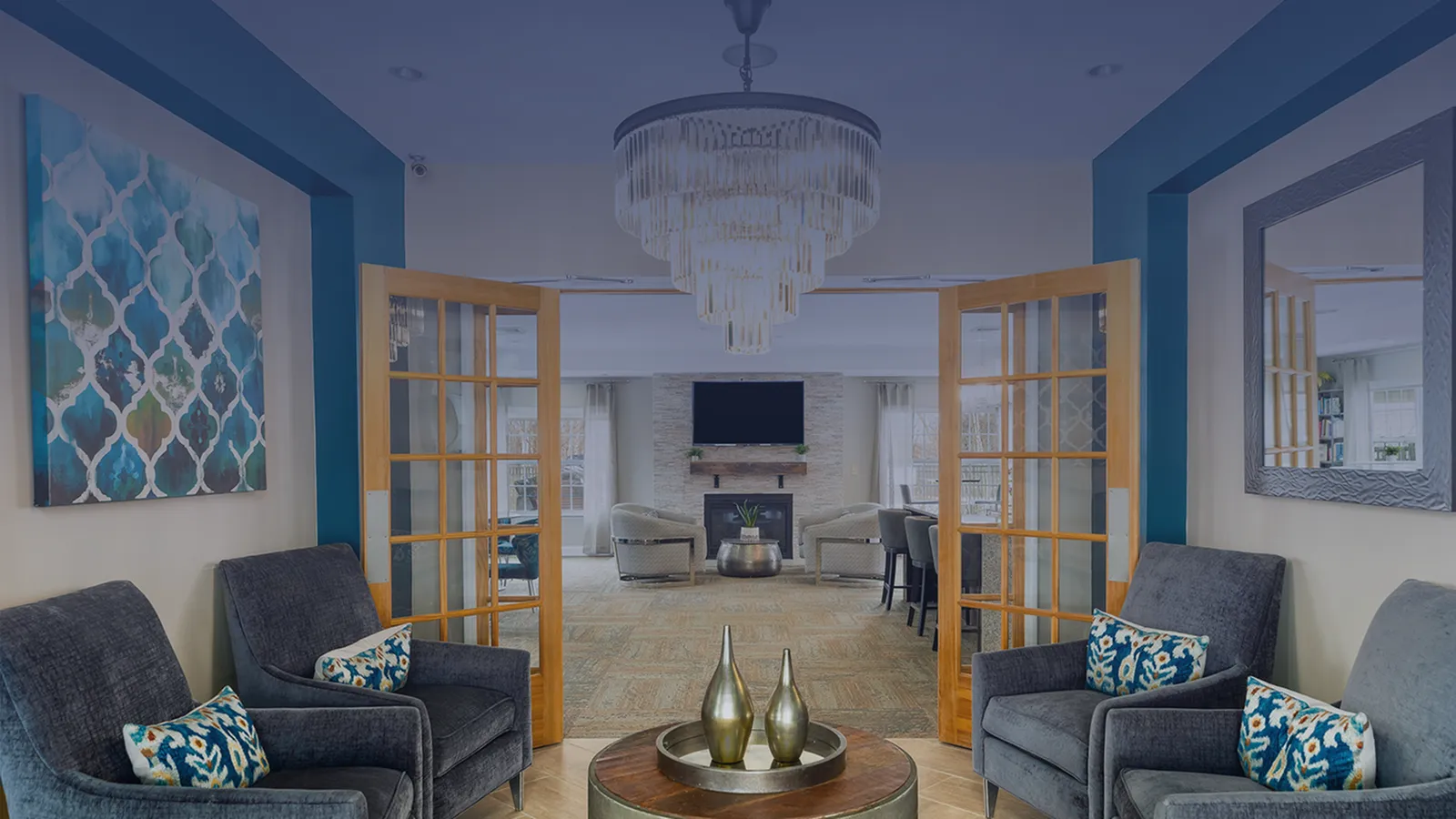 Luxurious living area with elegant chandelier, plush seating, and modern decor, leading to a cozy fireplace and dining space.