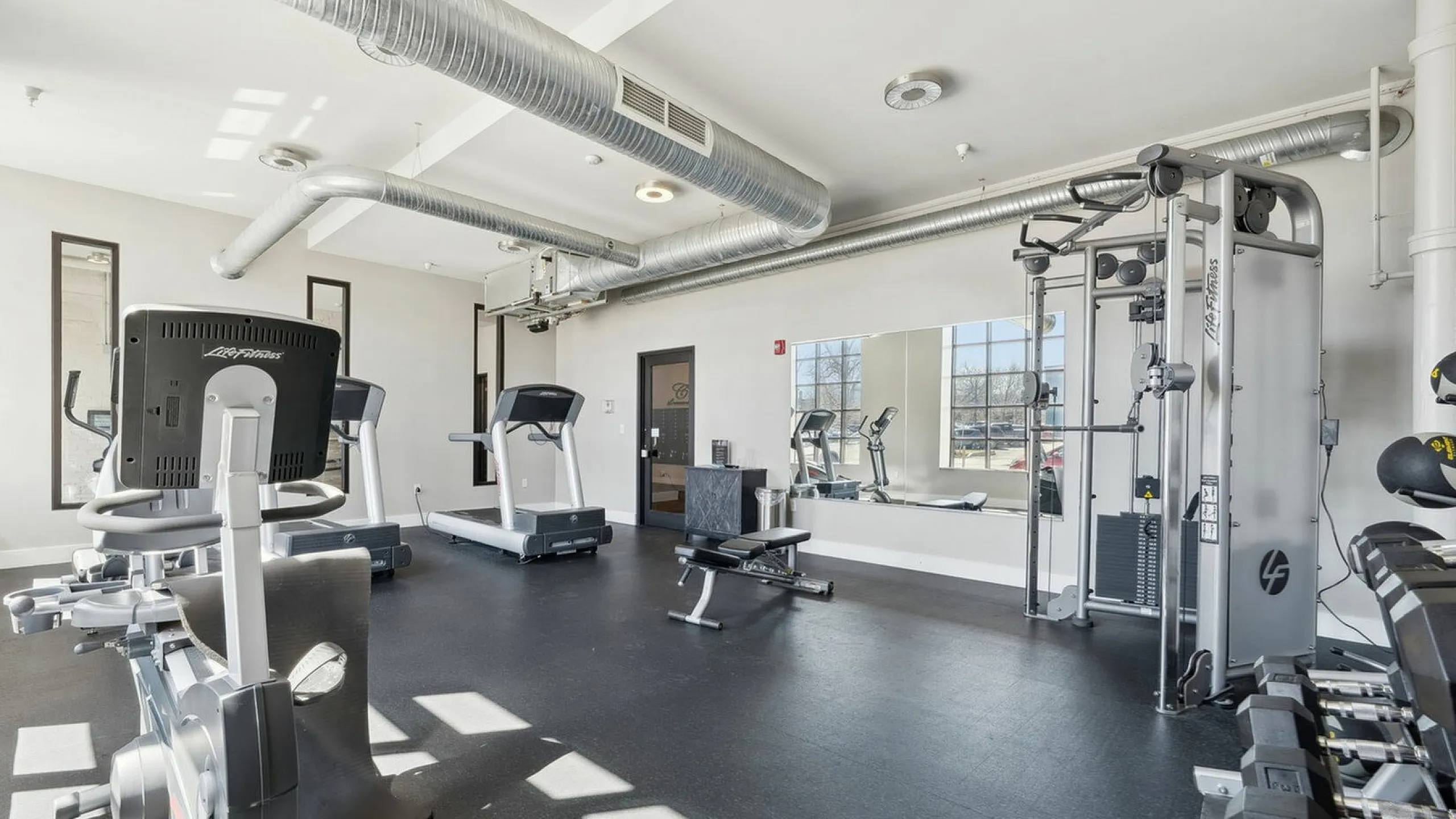 Modern fitness center with state-of-the-art equipment, including treadmills, exercise bikes, and weight machines, in a bright and spacious area.