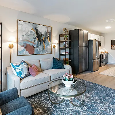 Elegant open-concept living area featuring a cozy sofa, stylish artwork, and a modern kitchen with sleek appliances.