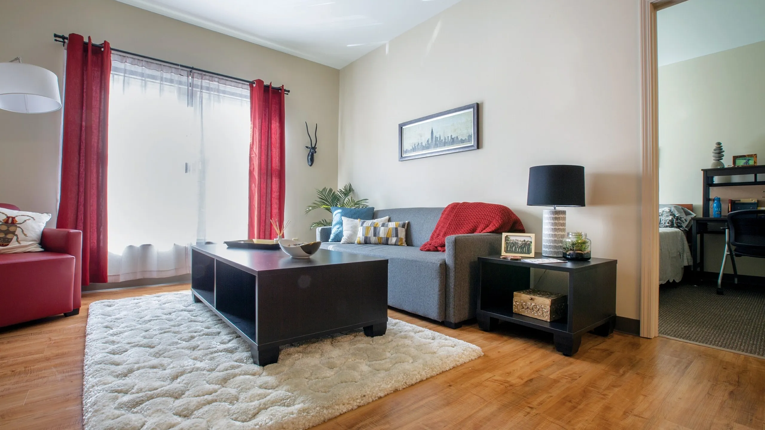 Inviting living room with large window, stylish furniture, and vibrant red accents creating a cozy atmosphere.