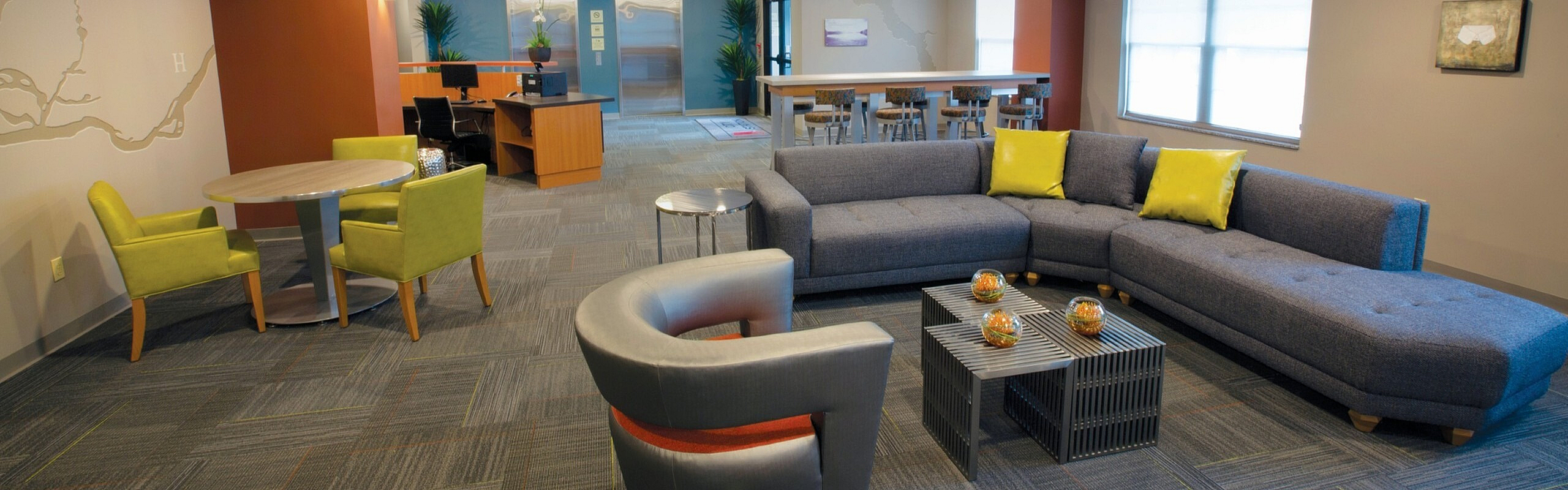 Modern lounge with stylish gray sectional sofa, vibrant yellow cushions, and sleek furniture, perfect for relaxation and social gatherings.