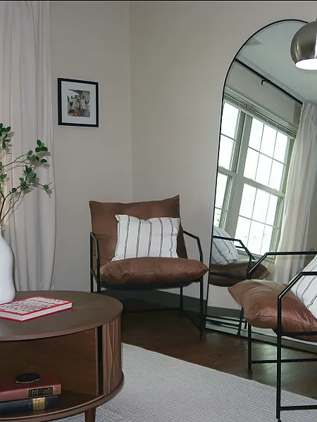 Cozy reading nook with a stylish chair, modern floor lamp, and elegant mirror, offering a serene ambiance.