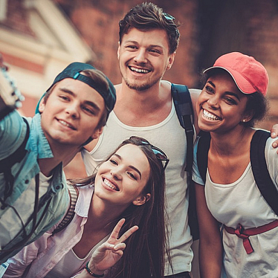 Group of friends joyfully taking a selfie outdoors, showcasing a vibrant and carefree mood.