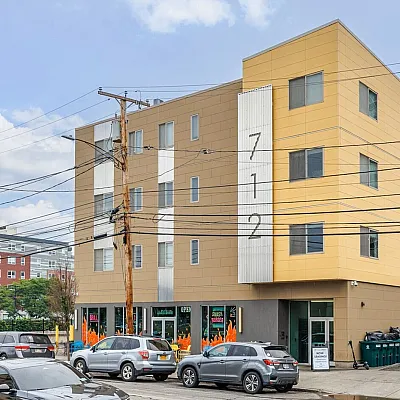 Modern urban apartment building with vibrant exterior and street-level shops.