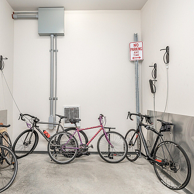 Contemporary apartment bike storage room featuring secure wall-mounted hooks and organized electric outlets.