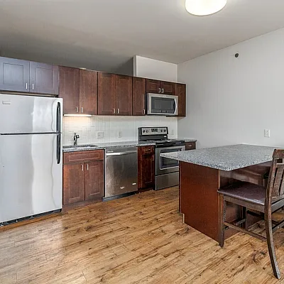 Modern kitchen with stainless steel appliances, elegant dark wood cabinets, and a granite breakfast bar with seating.