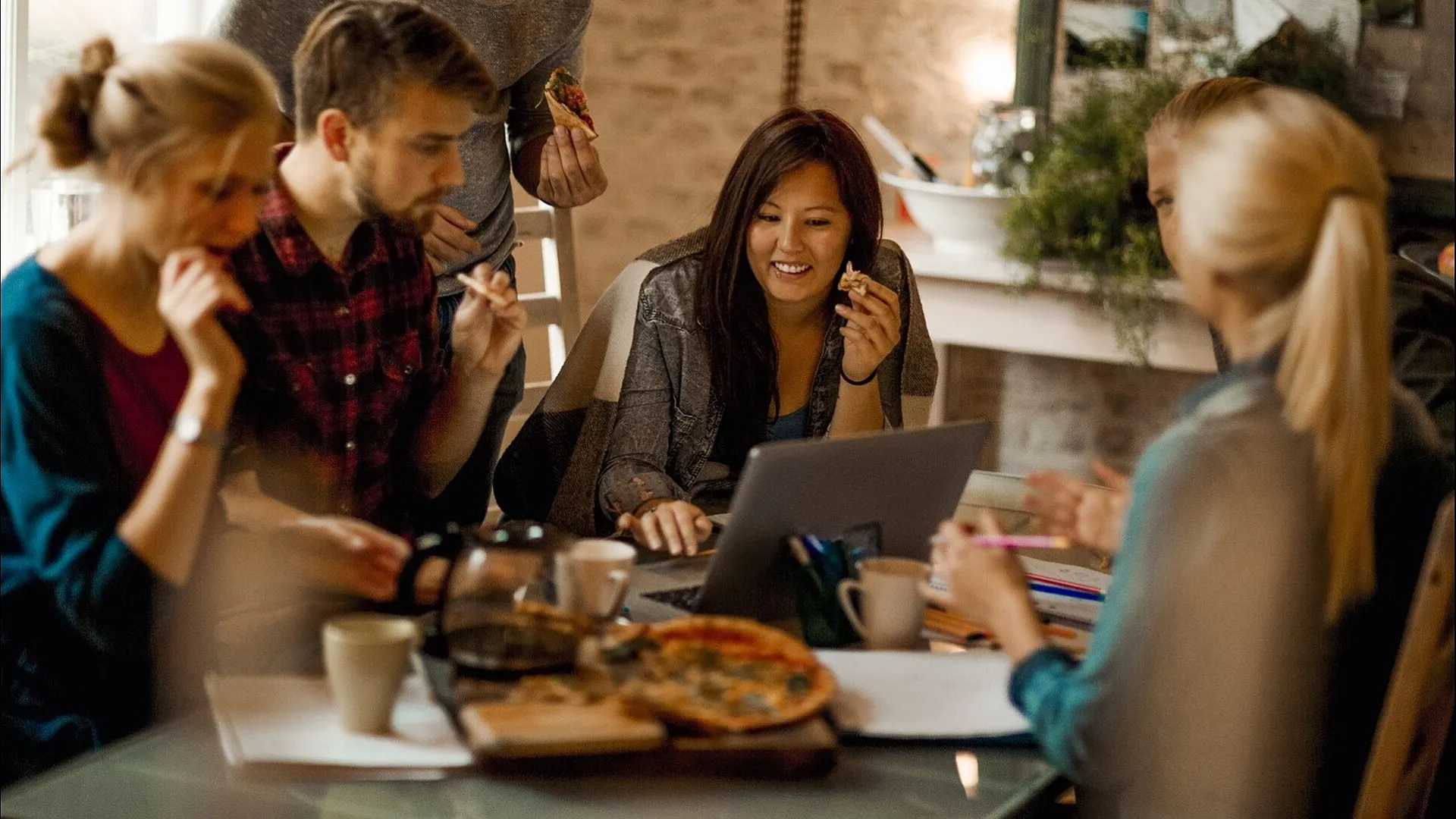 Group of friends enjoying pizza and laughter around a cozy table, glowing in natural light and confiding in a relaxed ambiance.