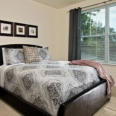 Inviting bedroom with elegant decor featuring a plush bed, stylish bedside lamp, and large window for natural light.