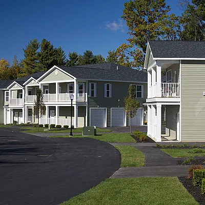 Kensington's charming residential community with modern two-story homes, featuring spacious balconies and lush landscaping under a clear blue sky.