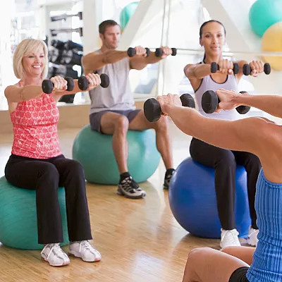 The Kensington's vibrant group fitness class in a state-of-the-art gym, featuring participants using exercise balls and dumbbells.