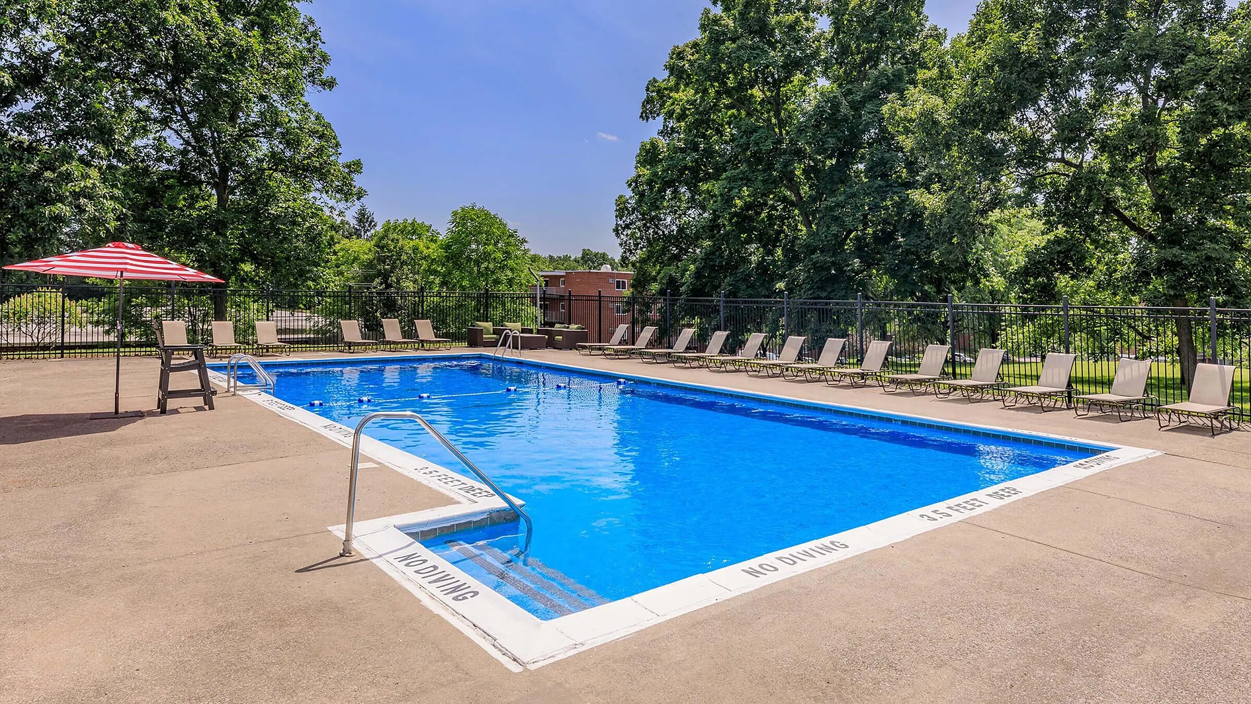 Inviting outdoor pool with lounge chairs and lush green surroundings, perfect for relaxation and leisure.