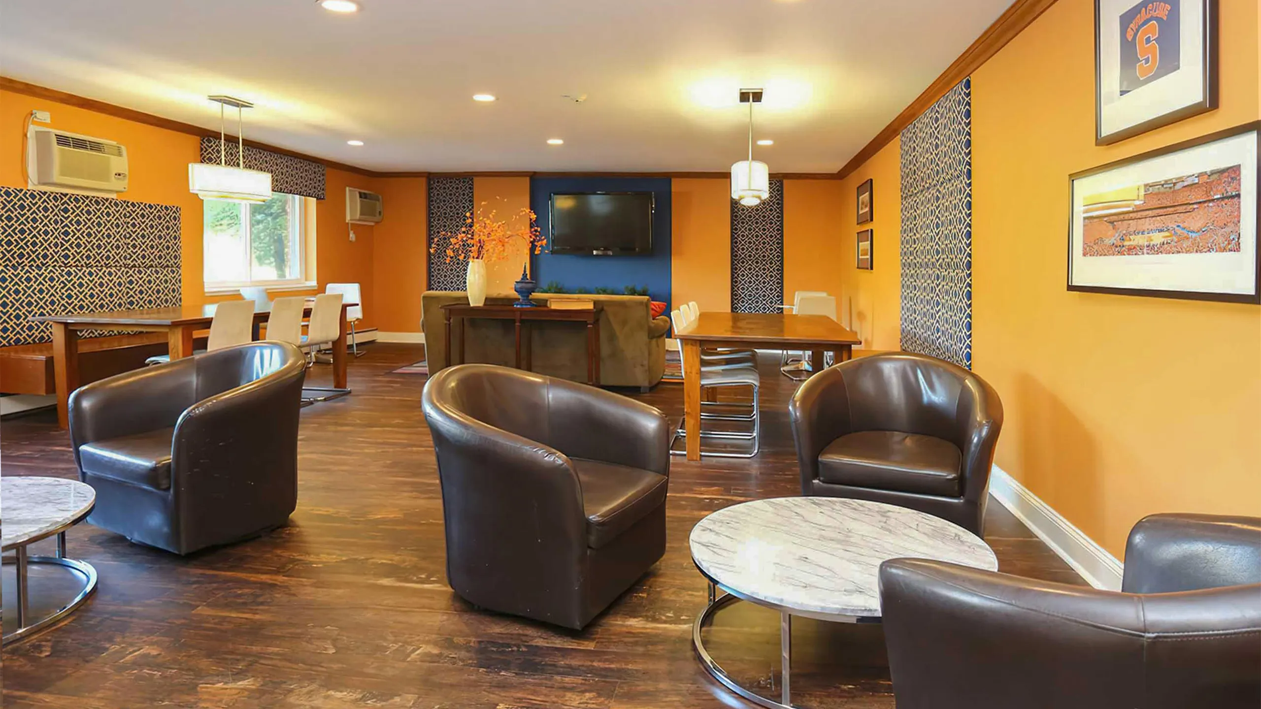 Vibrant and inviting lounge area with modern seating, stylish decor, and a cozy ambiance enhanced by warm orange walls.