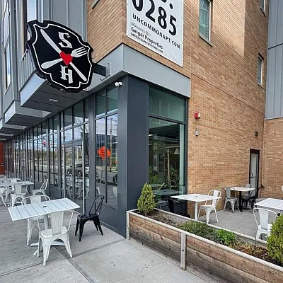 Chic urban outdoor seating area with modern metal chairs and lush planters, perfect for a relaxing coffee break.