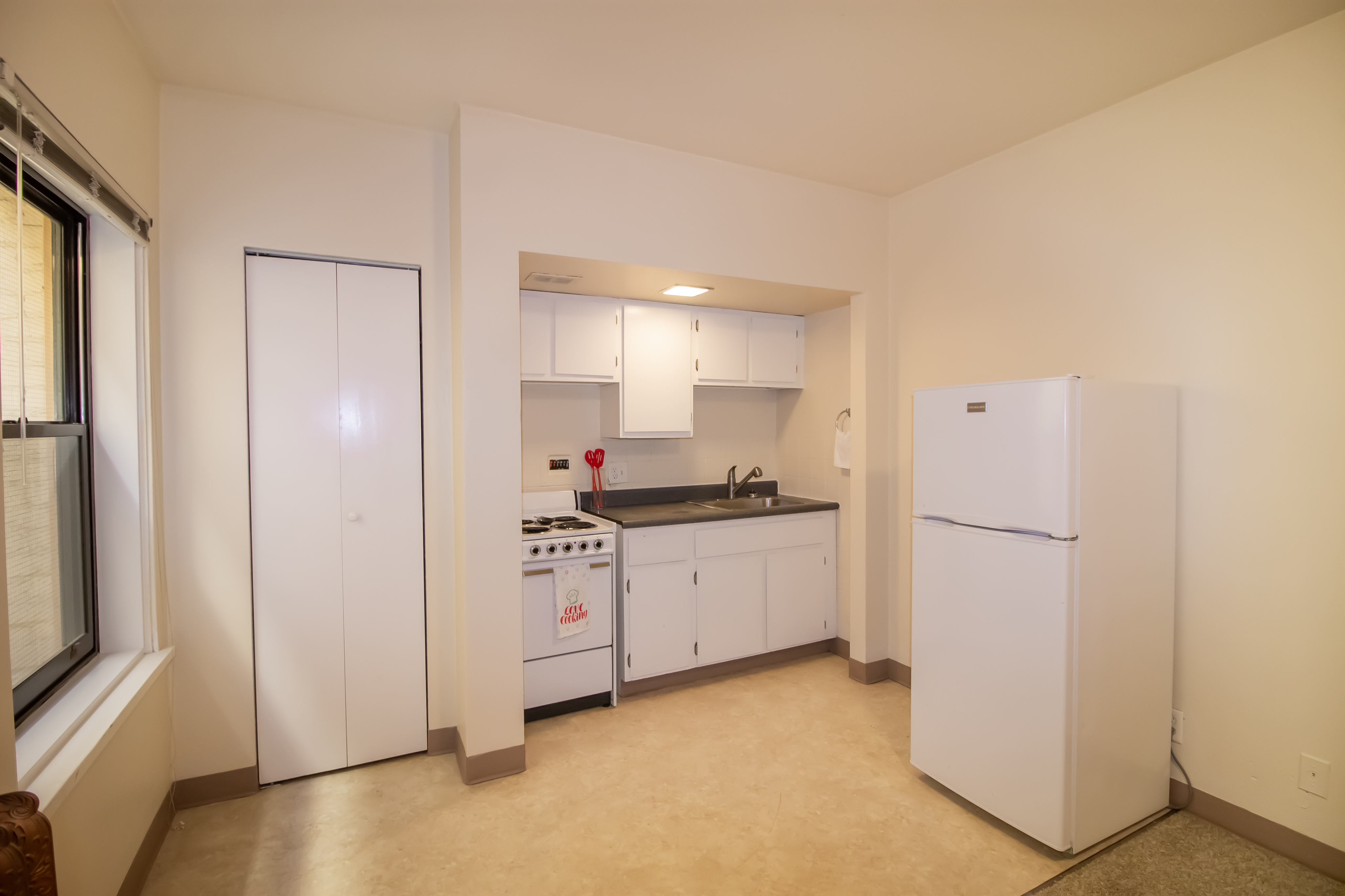 Bright, compact kitchen with modern appliances and ample storage space, featuring a large window for natural light.
