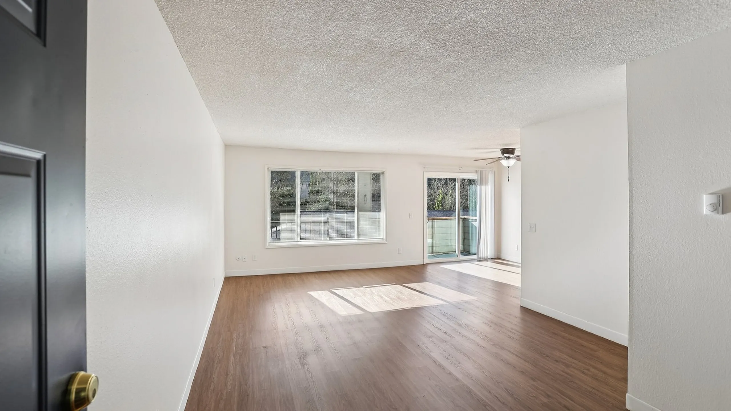 Bright and spacious living area with large windows, elegant wood flooring, and access to a private balcony, creating an inviting atmosphere.