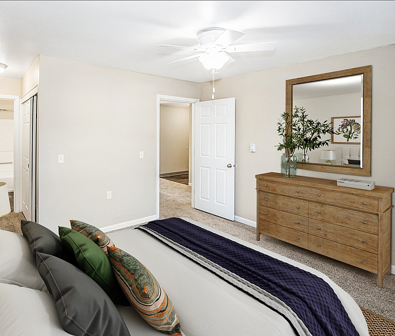 Bright and welcoming bedroom with plush bedding, elegant dresser with mirror, and modern ceiling fan.