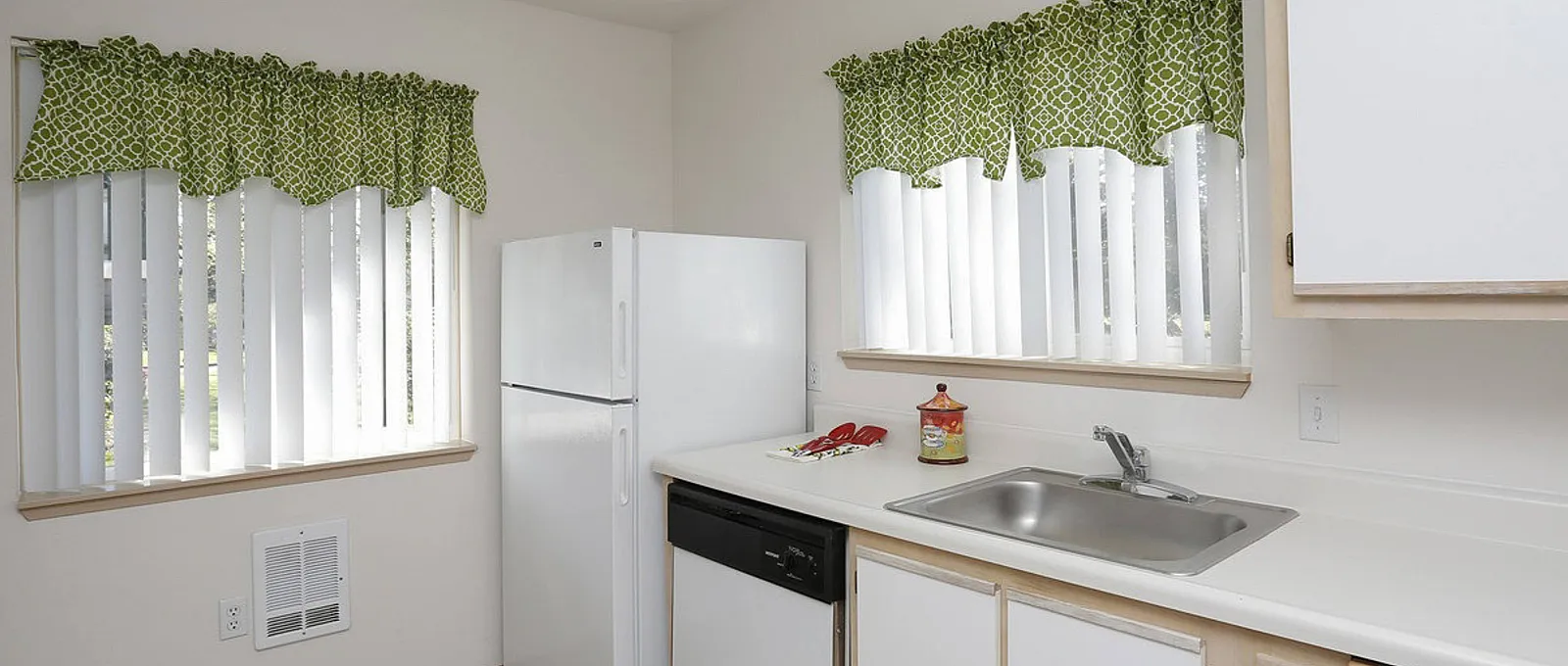 Charming kitchen with bright natural light, featuring sleek appliances, ample counter space, and stylish green curtains.
