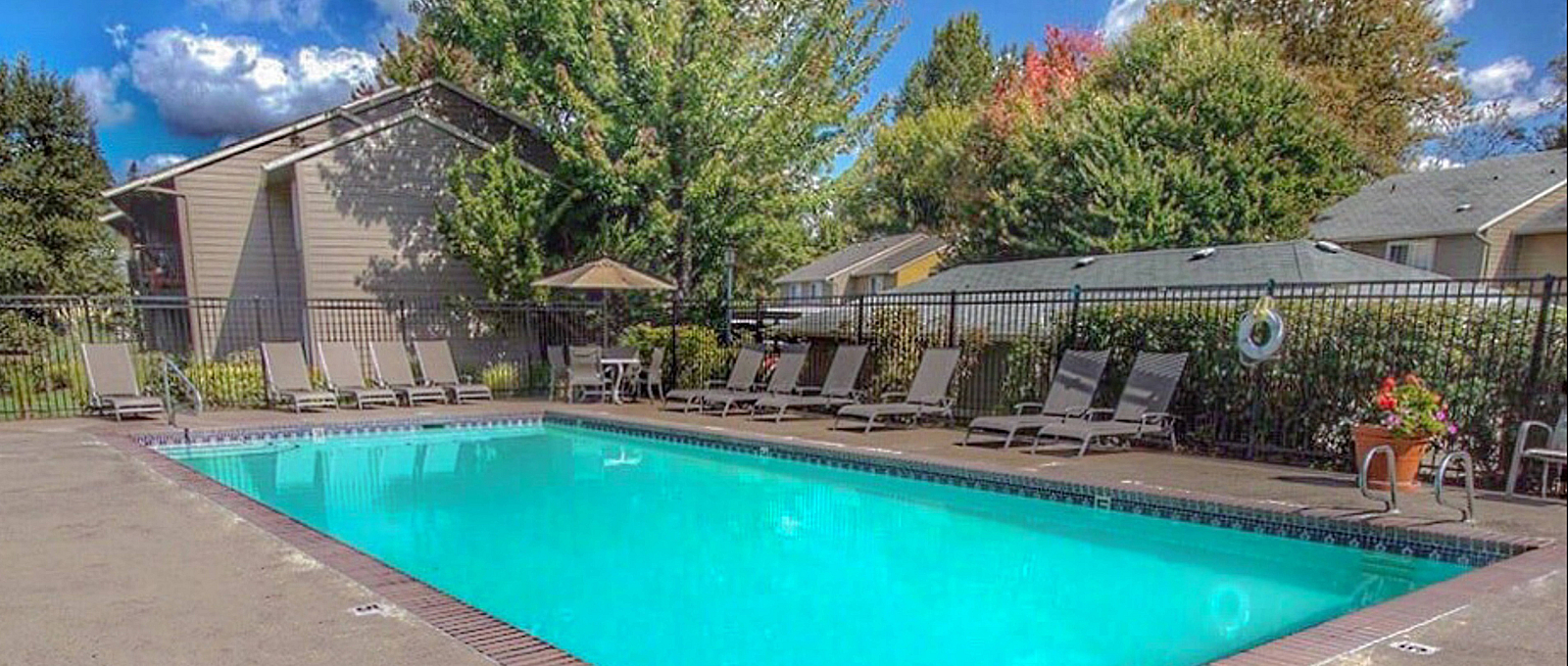 Inviting outdoor pool area with lounge chairs and lush greenery, perfect for relaxation and enjoying sunny days.