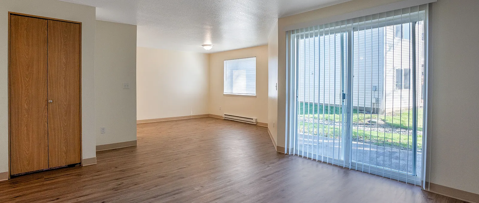 Bright and inviting living space with elegant wood flooring and large sliding glass doors leading to a serene outdoor view.