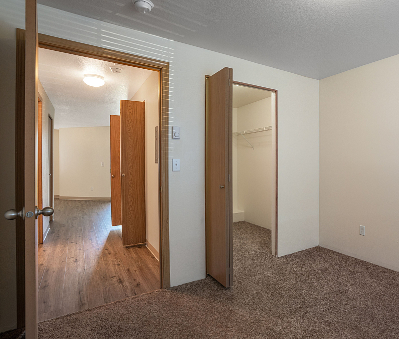 Inviting bedroom with plush carpet, ample natural light, and spacious closet, offering comfort and style.