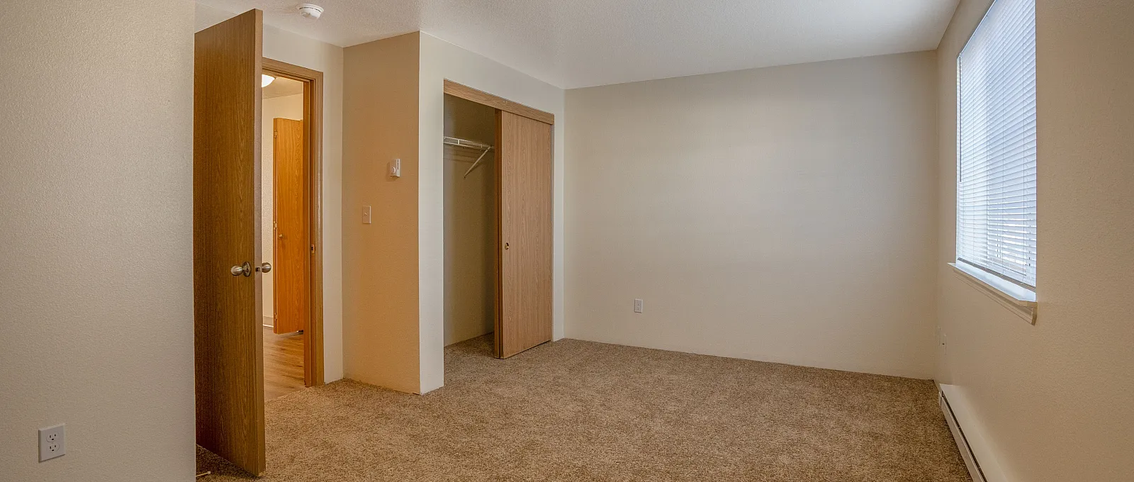 Inviting bedroom with soft carpeting, ample natural light, and a spacious closet featuring sliding doors.
