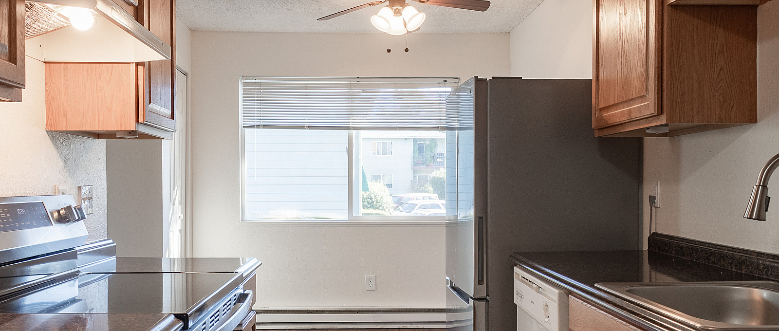 Sunlit kitchen featuring modern appliances, elegant wooden cabinetry, and sleek countertops.