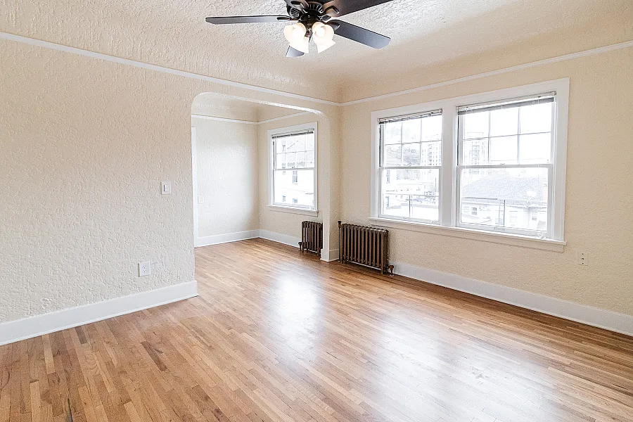 Bright and airy apartment with beautiful hardwood floors, large windows, and a ceiling fan, offering a welcoming living space.