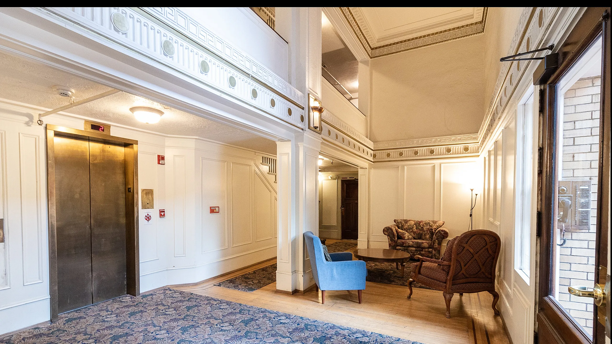 Elegant apartment lobby with vintage design, featuring comfortable seating and a classic elevator.