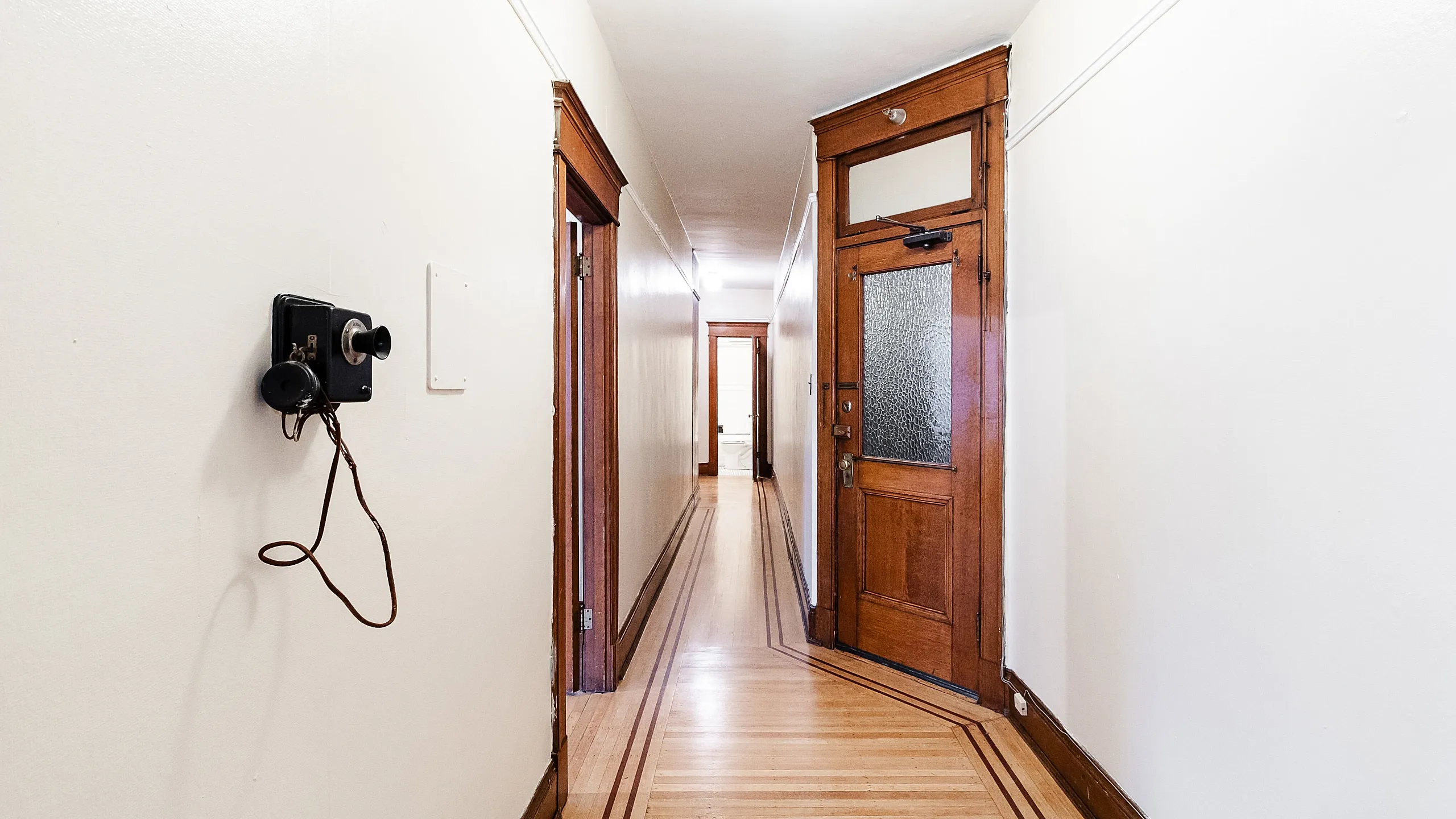 Charming hallway with vintage phone, elegant wooden trim, and inviting, warm lighting.