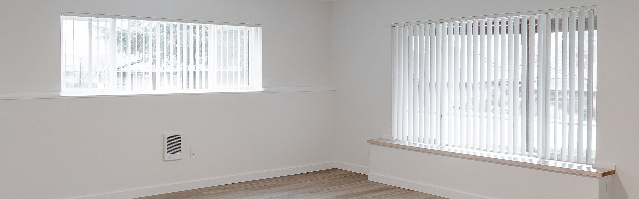 Bright and spacious living room with sleek wood flooring and large windows offering ample natural light.