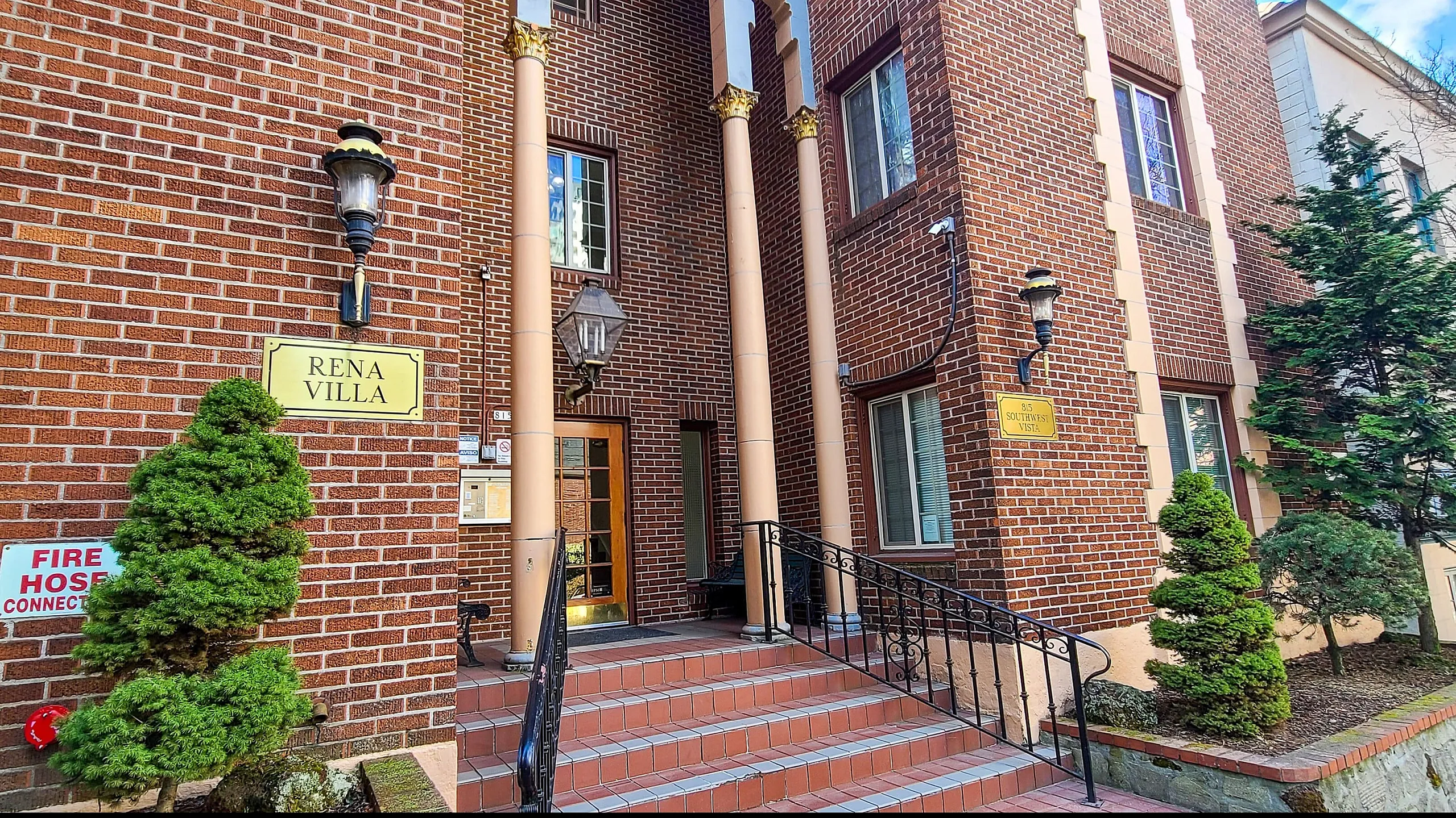 Elegant brick exterior of a charming villa with classical pillars and manicured shrubs.