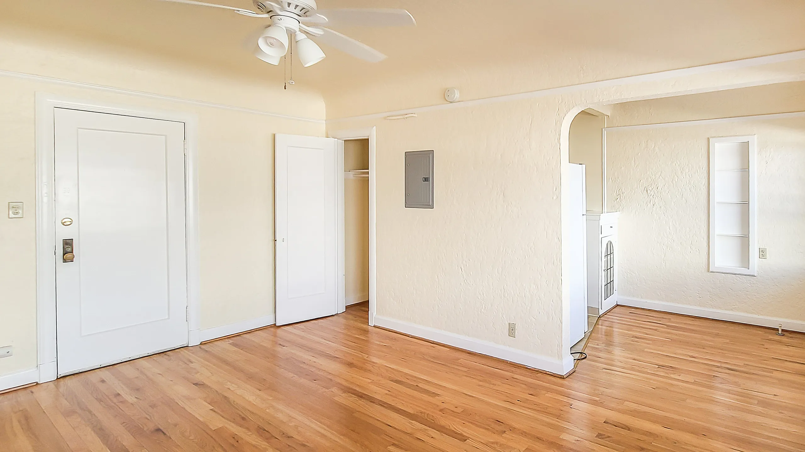 Charming apartment showcasing polished hardwood floors, fresh paint, and a cozy nook with built-in shelving.