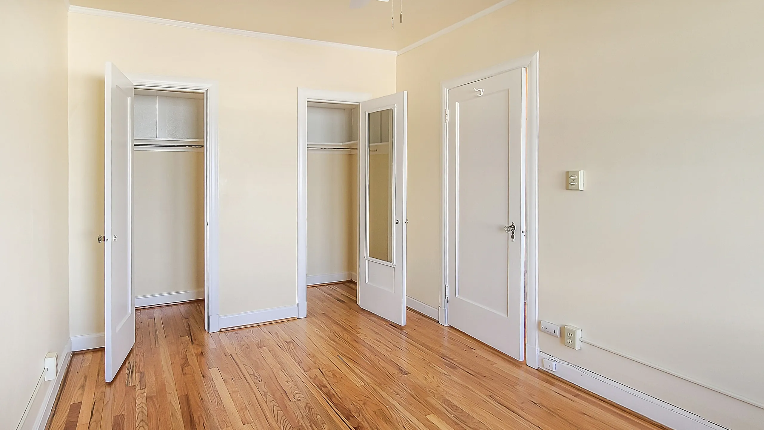 Bright and airy room featuring beautiful hardwood floors, fresh neutral walls, and ample closet space with elegant white doors.