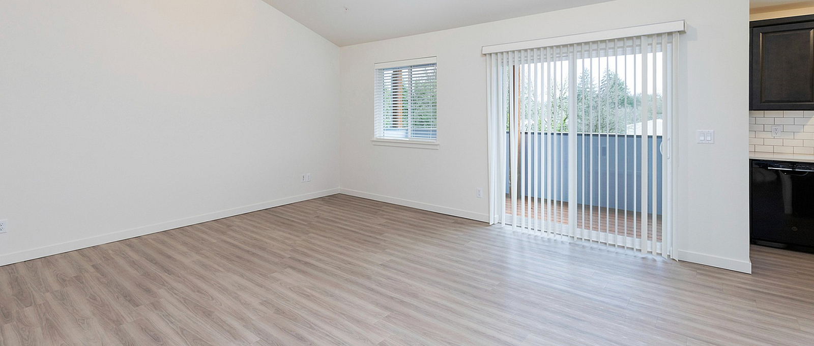Bright and airy living room with gleaming wood floors, large windows, and a sliding glass door leading to a charming balcony.