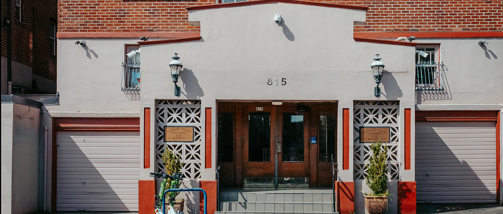 Charming brick apartment building with inviting entrance, decorative wall patterns, and sunny windows, offering urban living appeal.