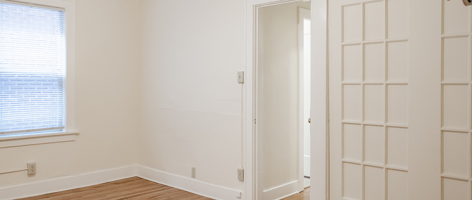 Bright and inviting room with beautiful hardwood floors, natural light from a large window, and elegant French doors.