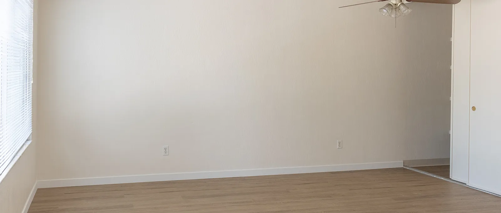 Bright, spacious room with elegant wood flooring and a stylish ceiling fan, perfect for cozy living.