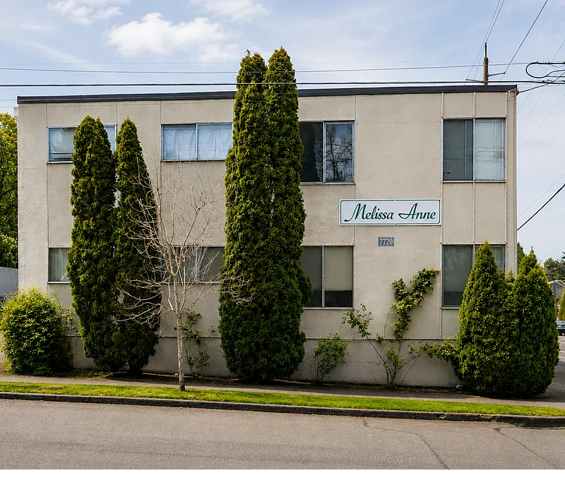Charming two-story apartment building with lush greenery, offering a serene living environment in a peaceful neighborhood.