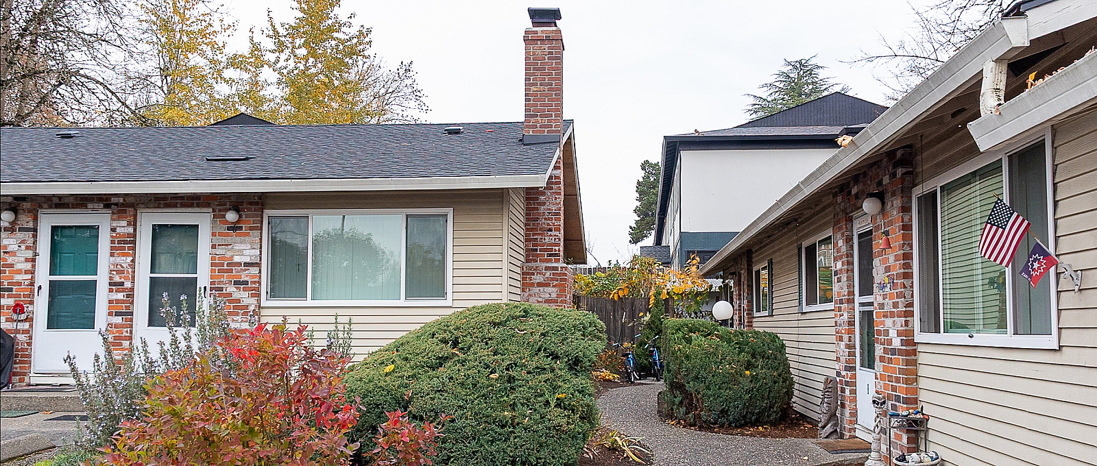 Charming suburban apartment with brick accents and manicured landscaping, featuring a welcoming entrance and cozy ambiance.